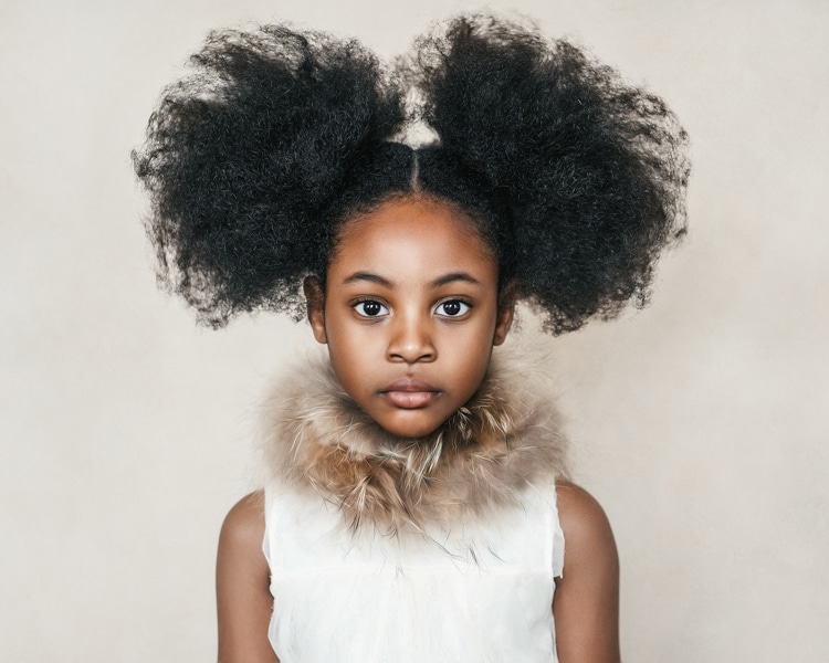 Girl with afro hair photographed with natural light on the creamy and light backdrop